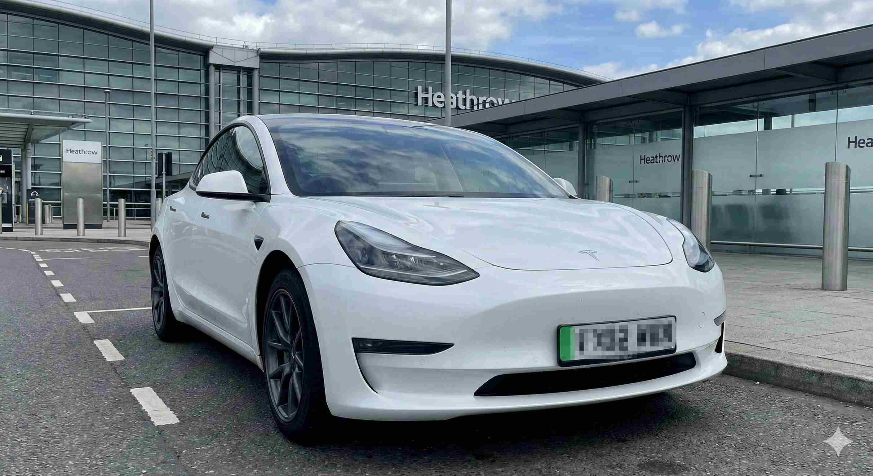 White Tesla Model 3 electric taxi at Heathrow Airport terminal - Professional airport transfer service from North Wales
